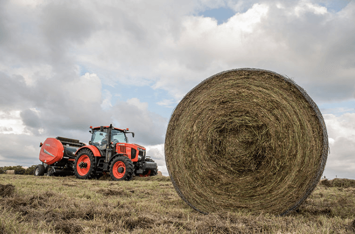 Tractor pulling hay baler with a close up shot of a hay bale