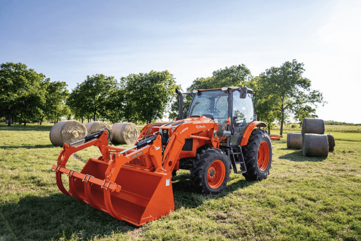Tractor featured in a field with hay bales