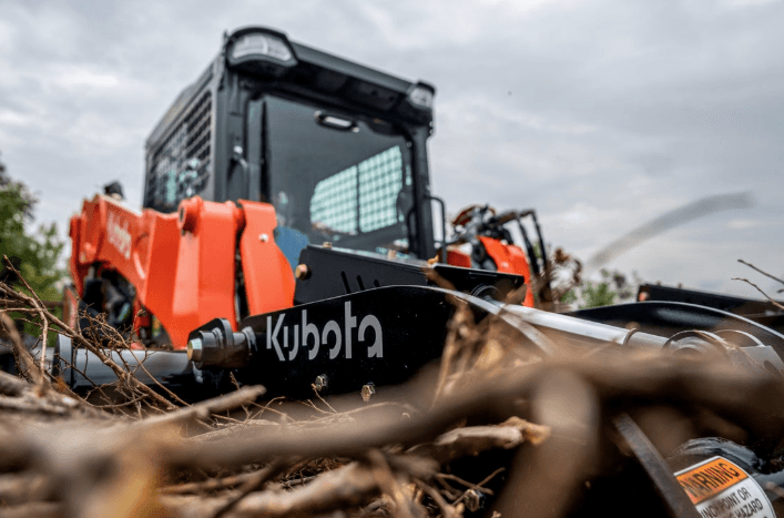 Close up shot of track loader moving branches