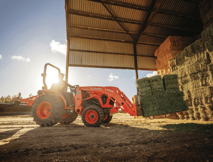 Kubota L Series tractor moving pallet of hay stacks