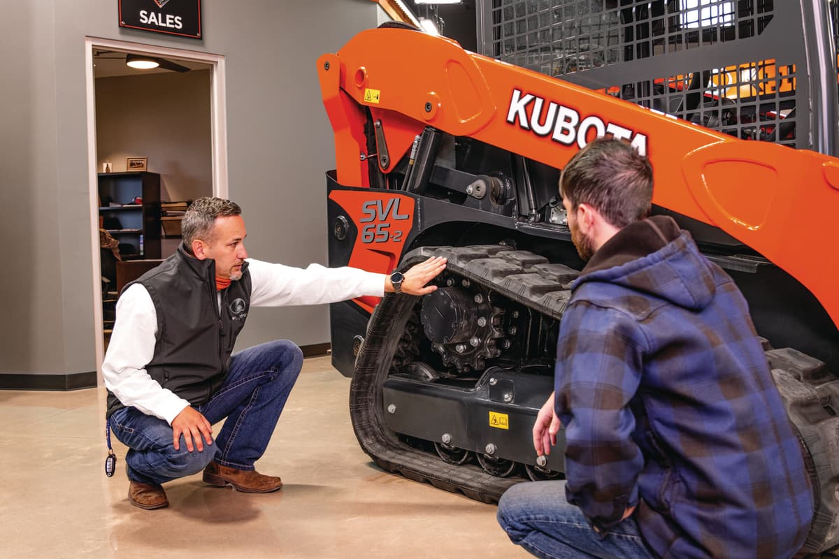 men looking at tracks of kubota track loader