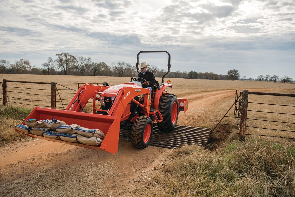man driving feed over cattle grate with L3560