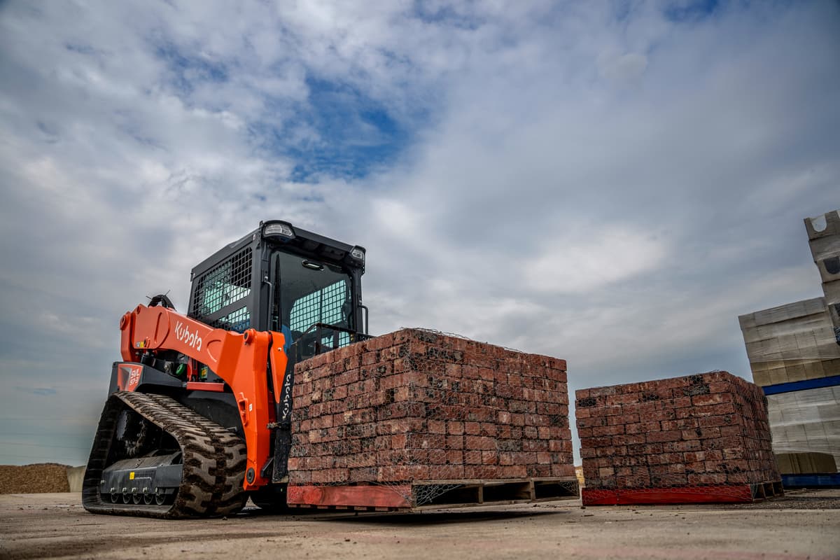 Kubota SVL97-3 transporting a pallet of bricks